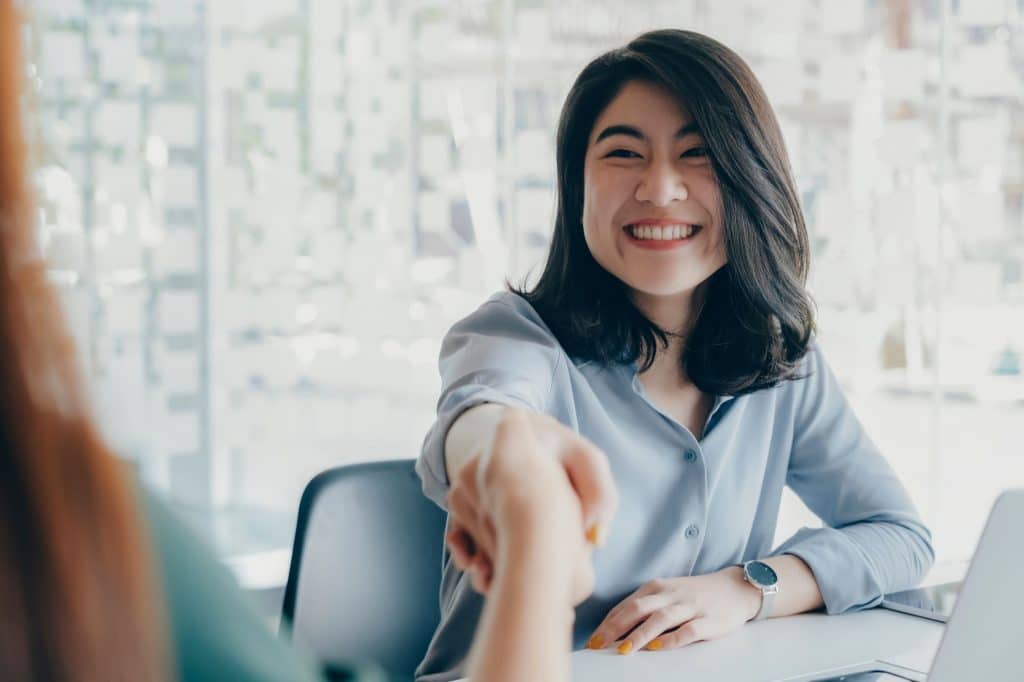 A young female business owner shaking hands.