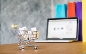 a tiny shopping cart in front of a laptop